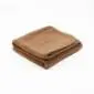 Folded brown camel and merino wool mattress topper with a textured surface and stitched edges.