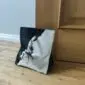 358025400_280482711131064_1385718542148045241_n Square black and white cowhide door stopper with a knotted rope handle on a wooden floor.