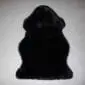 A natural shaped black sheepskin rug with thick, soft wool pile.
