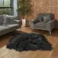 A large black Icelandic sheepskin rug with long, thick wool on a wooden floor.