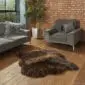 Hide Rugs_Lifestyle_0022 A large, dark brown rare breed double sheepskin rug with thick, textured wool on a wooden floor.