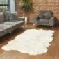 Large ivory four-skin British sheepskin rug with a natural scalloped edge on a wooden floor.
