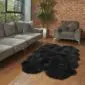 Large black quad sheepskin rug with a thick, textured pile and natural scalloped edges on a wooden floor.