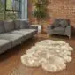 Large quad stone sheepskin rug with a thick, natural wool pile and scalloped edges on a wooden floor.