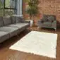 Rectangular ivory shorn sheepskin rug with straight edges on a wooden floor.