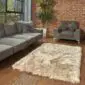 Rectangular stone-coloured sheepskin rug with a thick, textured pile on a wooden floor.