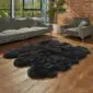 Large black sexto sheepskin rug with a natural scalloped edge on a wooden floor.