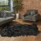 Large black Icelandic sheepskin rug with long, shaggy wool on a wooden floor.