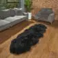Long, black double sheepskin rug with a thick, textured wool pile on a wooden floor.