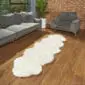 Long ivory double sheepskin rug with a natural scalloped edge on a wooden floor.