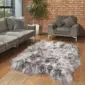 Large grey and white Icelandic sheepskin rug with long, thick wool on a wooden floor.