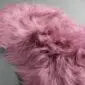 IMG_0901 Close-up of a dusty rose Icelandic sheepskin rug with long, wavy wool fibres.