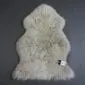 Oyster coloured curly sheepskin rug in a natural pelt shape with a textured wool pile.