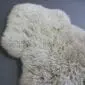 Oyster-coloured curly sheepskin rug with a natural pelt shape and thick textured wool.