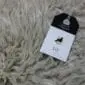 Close up of a light grey curly sheepskin rug with a black and white product tag.