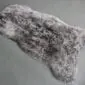 Irregularly shaped grey shorn Icelandic sheepskin rug with a thick, textured wool pile.