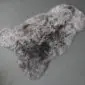 Natural grey shorn Icelandic sheepskin rug with a thick, curly wool texture and organic shape.