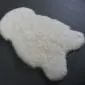 Ivory shorn Icelandic sheepskin rug with a natural pelt shape and thick, curly wool texture.