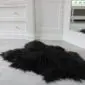 Long-haired black Icelandic sheepskin rug with a natural, irregular shape and thick, shaggy texture.