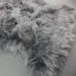 Close-up of a grey sheepskin rug with long, thick, textured wool fibres.