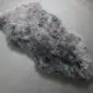 Natural grey sheepskin rug with thick, textured wool and an irregular organic shape.
