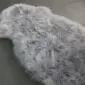 Steel grey sheepskin rug with a natural organic shape and thick, textured wool pile.