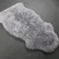 Irregularly shaped steel grey sheepskin rug with thick, textured wool pile.