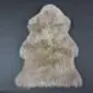 Natural stone-coloured sheepskin rug with a thick, textured pile and organic pelt shape.