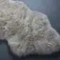 Small stone grey sheepskin rug with thick, textured wool and a natural organic shape.