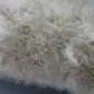 Close-up of a stone grey sheepskin rug with thick, textured wool fibres.