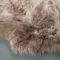Close-up of a thick, long-pile sheepskin rug in shades of taupe and cream.