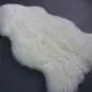 Natural ivory white sheepskin rug with thick, textured wool pile and organic curved edges.