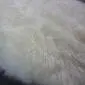 Close-up of a thick, ivory-coloured sheepskin rug with long, soft wool fibres.