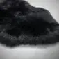 Close-up of a black sheepskin rug with thick, textured wool pile.