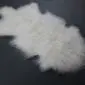 Ivory Mongolian lambskin rug with long, curly wool fibres and an irregular natural shape.