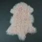 Blush pink Mongolian lambskin rug with long, curly wool fibres on a dark grey background.