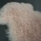 Blush pink Mongolian lambskin rug with long, curly wool texture.