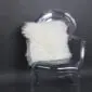 Square ivory Mongolian sheepskin cushion with long, curly wool texture resting on a .