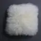 Square ivory sheepskin cushion with long, fluffy wool texture.