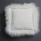 Square ivory sheepskin cushion with a long, fluffy wool trim .