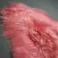 Long-haired Icelandic sheepskin rug in light coral pink with a natural, shaggy texture.