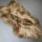 Long-haired Icelandic sheepskin rug in rusty brown and cream tones with a natural, irregular shape.