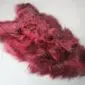 Long-haired Icelandic sheepskin rug in burgundy red with a natural hide shape.