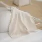 Ivory merino wool kids blanket with a soft, textured finish and stitched edges laid flat.