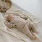 A baby lying on a textured ivory merino wool blanket with a ribbed knit pattern.