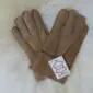 A pair of light brown suede children's gloves with visible stitching and a white product tag.