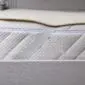 Ivory merino wool mattress topper with a textured fleece surface layered on a white quilted mattress.