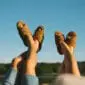 Two pairs of brown wool slippers with fluffy linings being worn outdoors.