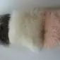 Ivory Mongolian sheepskin cushion with long, curly wool texture shown alongside grey and pink cushions.