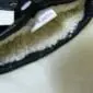 Close-up of a black leather glove cuff showing a thick, cream-coloured sheepskin wool lining.